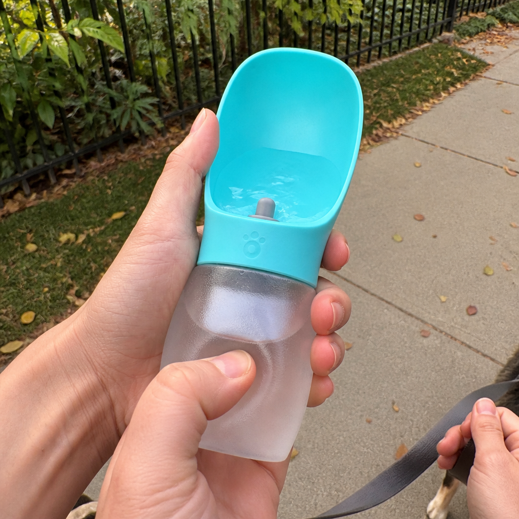 Hand squeezing the bottle so water rises into the built-in scoop