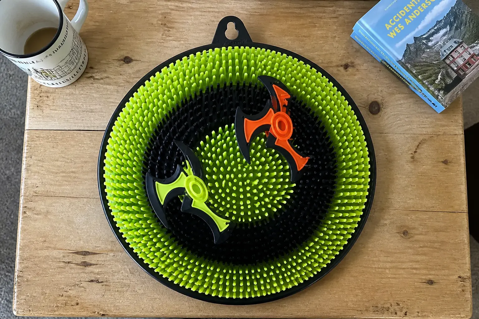 The 12-inch green-ring bristle target with multiple foam axes and ninja stars stuck across the rings, shown to scale