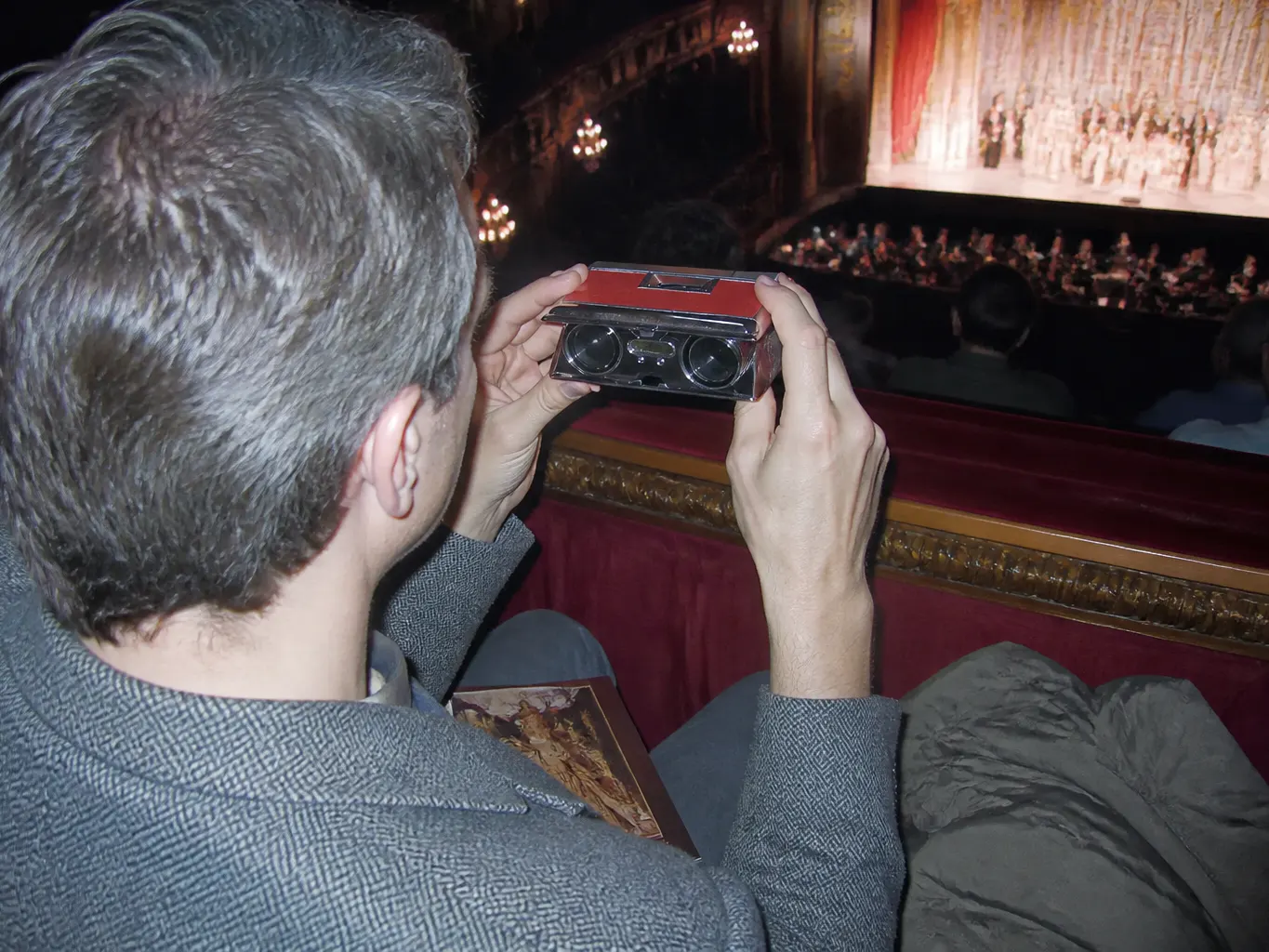 The opera glass being passed between two people in a row of theatre seats