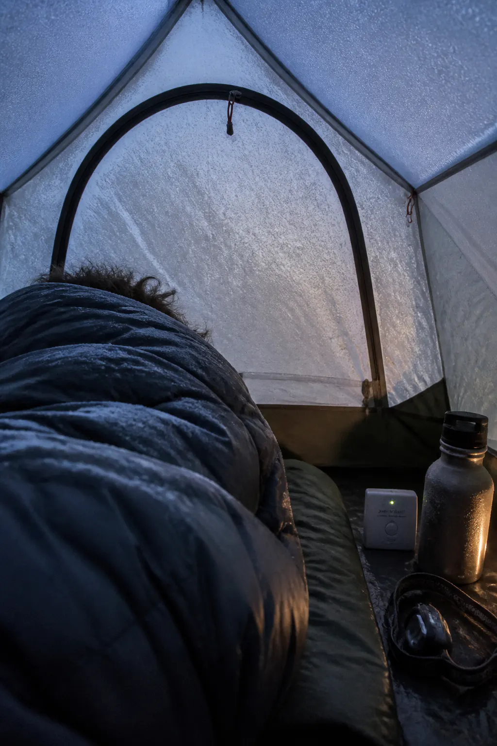 A frosted tent flysheet in the cold grey light before dawn
