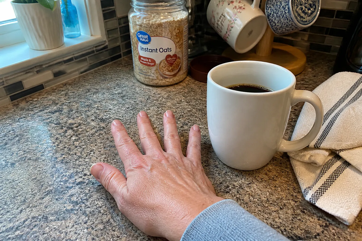The same morning coffee mug, weeks later, held by a hand with stronger nails
