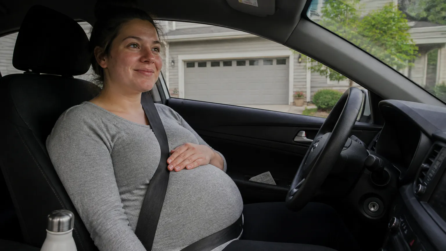 Pregnant woman calm in her car with the belt held below her bump