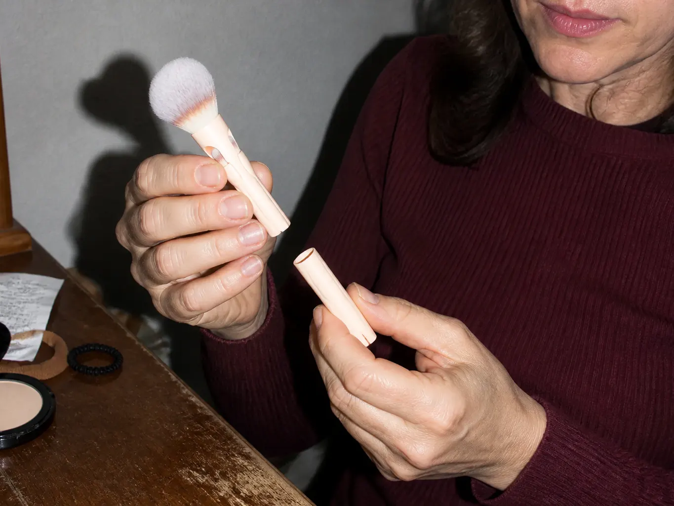 A woman holding the brush up at a dining table