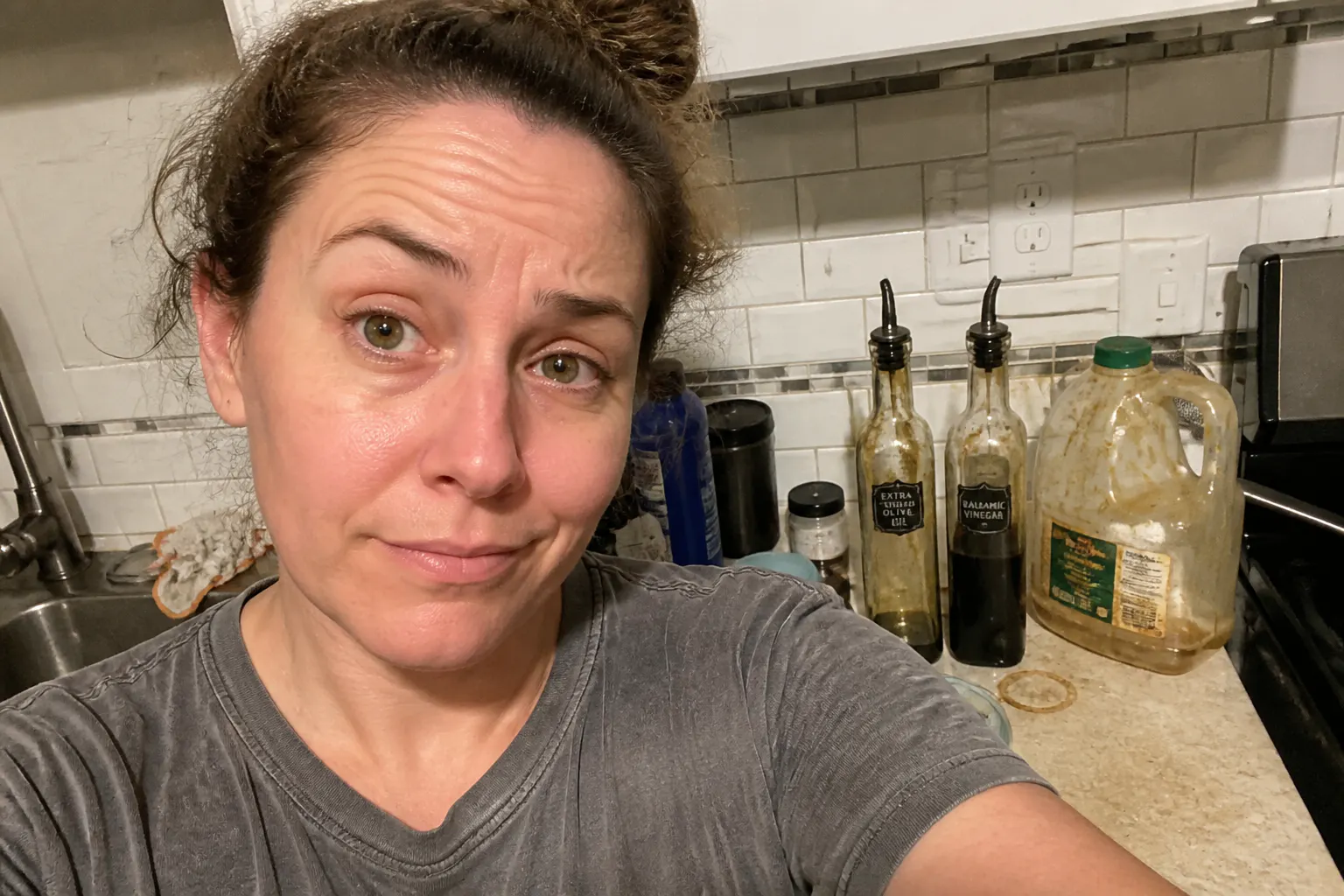 Cluttered kitchen counter with oil jug and vinegar bottle