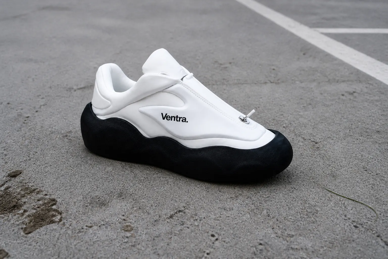 Football boot with matte-black CleatShield on raw concrete