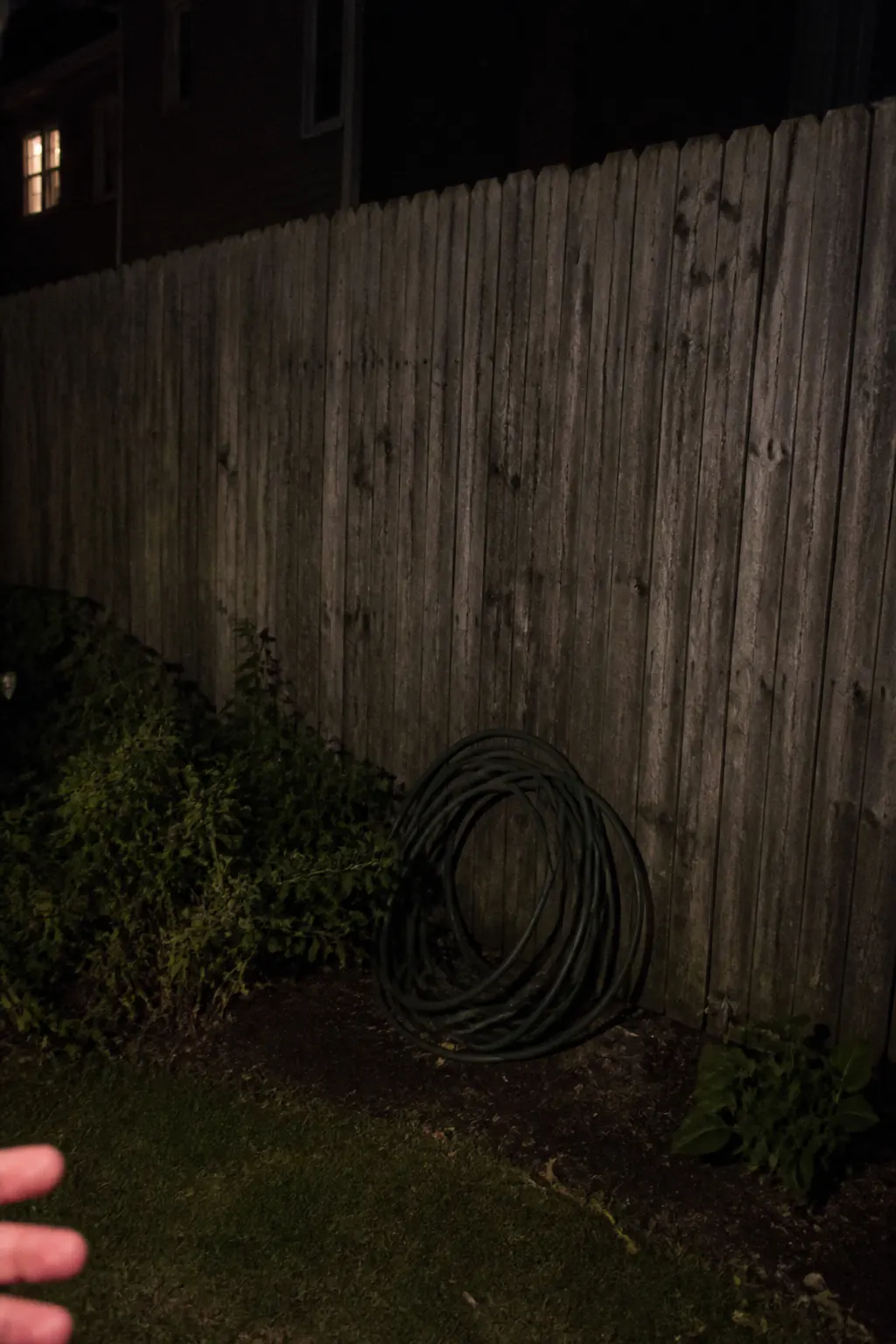 A plain dark backyard fence at night before the lights