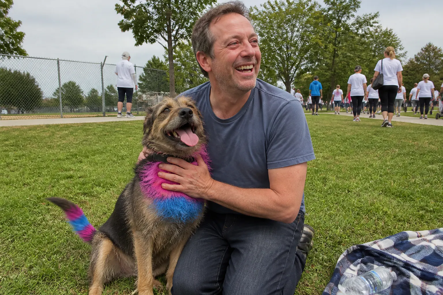 A dog with a bright blue and magenta tail tip on a sunny sidewalk