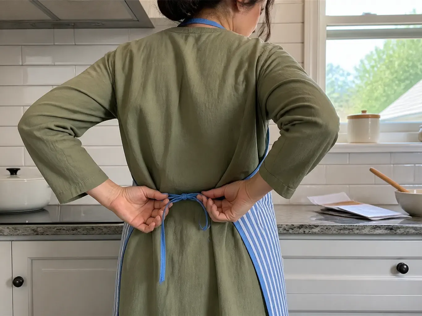 Hands knotting the rear waist ties behind the back