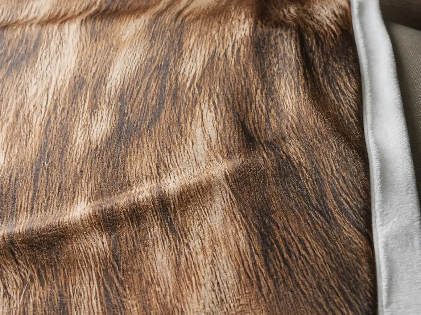 Extreme close-up of the spotted deer hide print showing irregular cream spotting and tonal shading