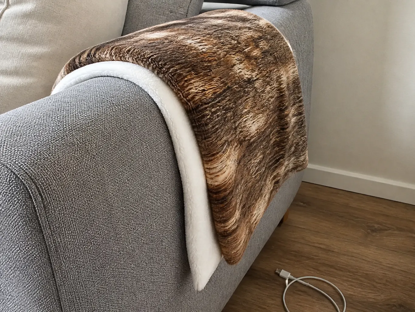 The throw draped over a sofa arm, falling soft rather than stiff