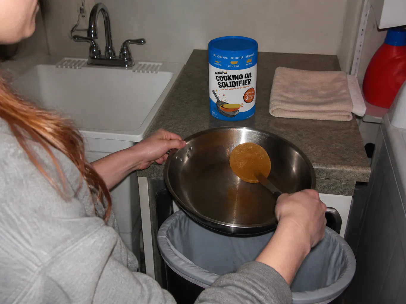 A shallow layer of bacon grease in a pan with a half scoop of white powder being sprinkled in
