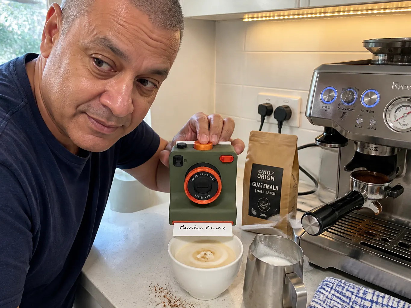 The camera held above a tall latte glass on a kitchen counter