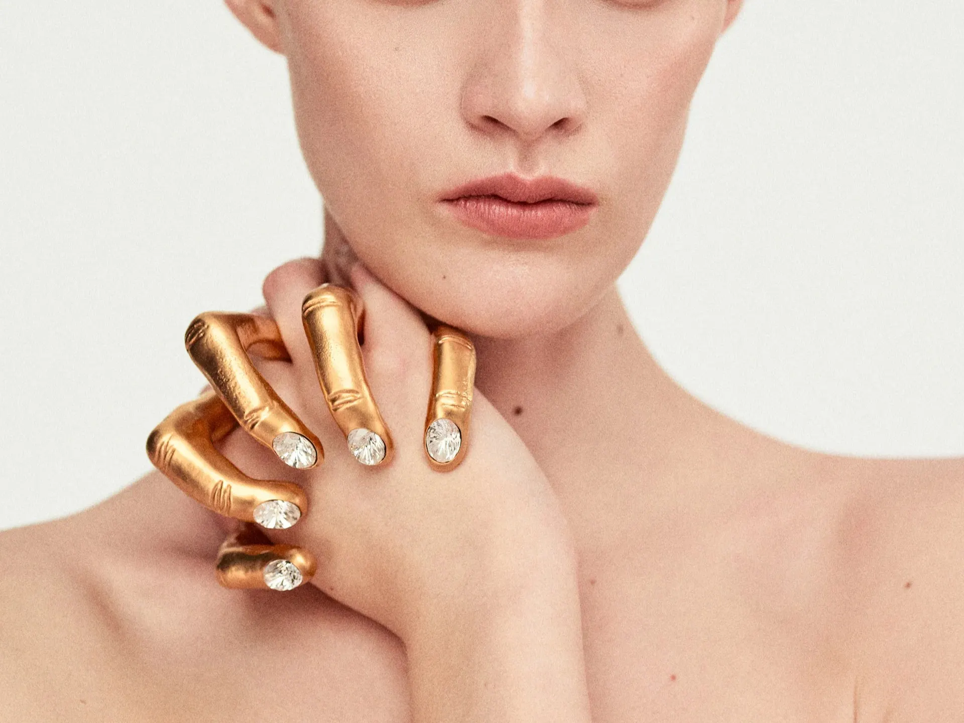 Sculpted golden hand ring with crystal-set nails on a finger